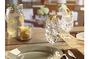 A close-up of a table setting featuring clear glasses of lemon water filled with large, hard Hoshizaki crescent ice, set in a bright, modern restaurant environment