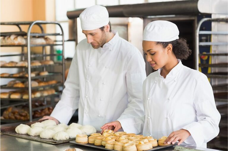 Two chefs or bakers prepare fresh dough and pastries in a kitchen, which relies on Hoshizaki roll-in or roll-through refrigeration for bulk storage