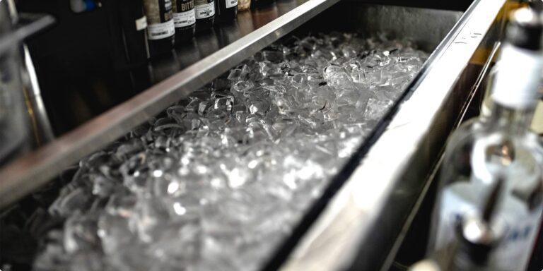 Clear, crescent-shaped Hoshizaki ice cubes fill a stainless steel bar well, ready for cocktail and beverage service