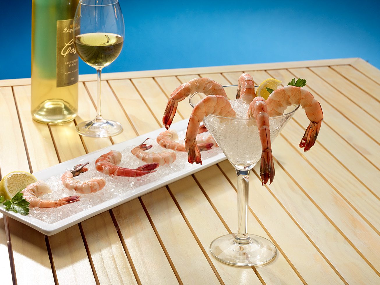 Shrimp cocktail and white wine displayed on a bed of Hoshizaki flaked ice on a white platter and in a martini glass