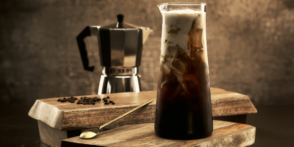 Hoshizaki crescent ice melts in a tall glass of iced coffee topped with cream