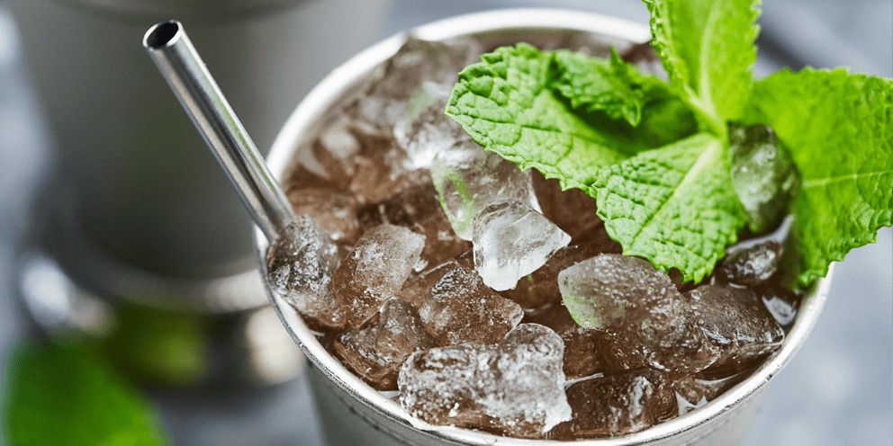 A close-up of a refreshing cocktail in a silver cup, garnished with mint leaves and filled with crushed ice produced by a Hoshizaki flaked ice machine