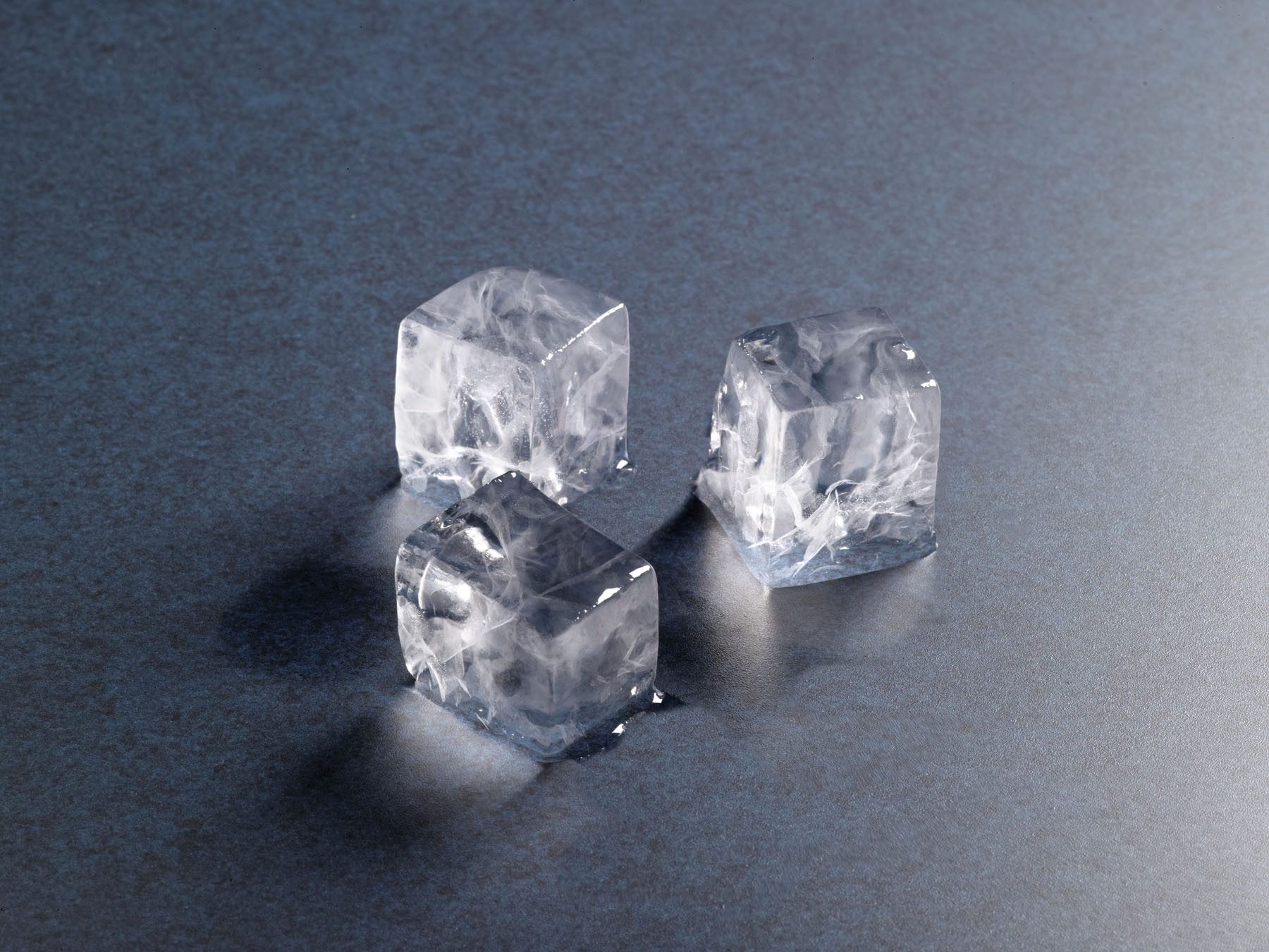 Three clear, square Hoshizaki ice cubes melting on a metallic surface